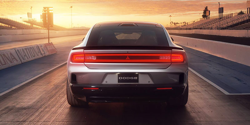A silver 2025 Dodge Charger Daytona EV from the back with its rear lights lit.
