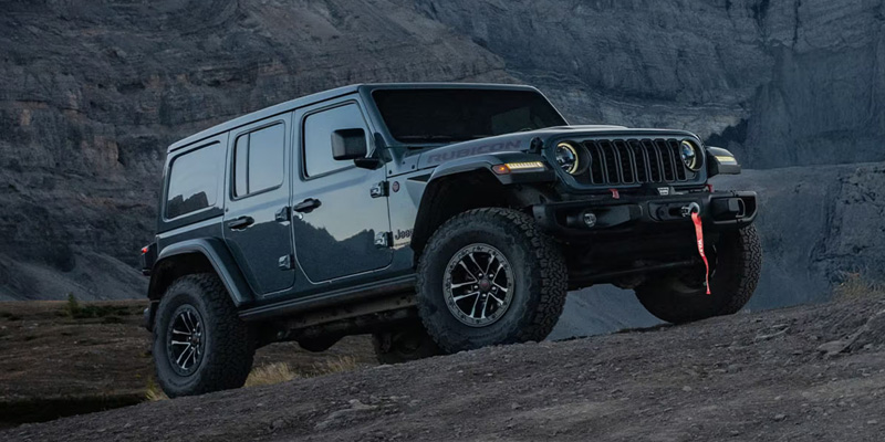 A dark grey Jeep Wrangler Rubicon parked on a rocky incline.