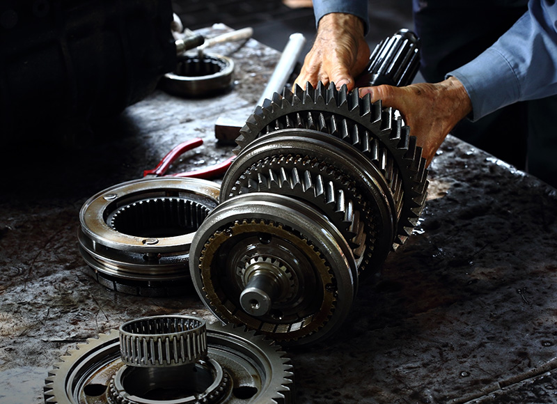Mechanic assembling metal gears on a greasy workbench.