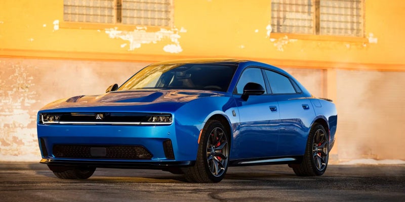 A blue 2026 Dodge Charger shines under the sunshine parked beside a yellow windowed building
